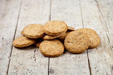 Fresh baked oat cookies heap on rustic wooden table.