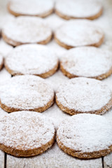 Fresh baked oat cookies with sugar powder closeup on rustic wooden table.