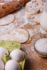young woman in apron kneading dough on board