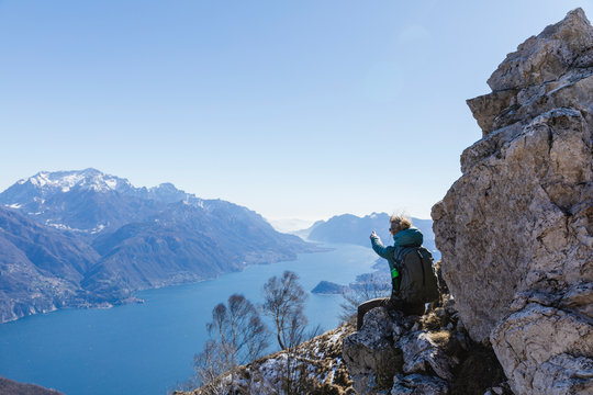 Italy, Como, Lecco, woman on a hiking trip in the mountains above Lake Como sitting on a rock enjoying the view