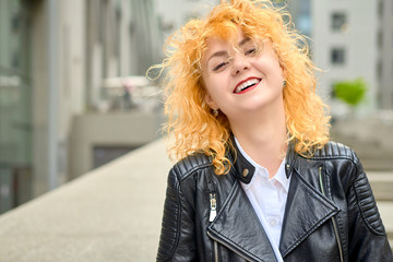 curly blonde young woman enjoying the walk in the city and feels happy in the modern cityscape