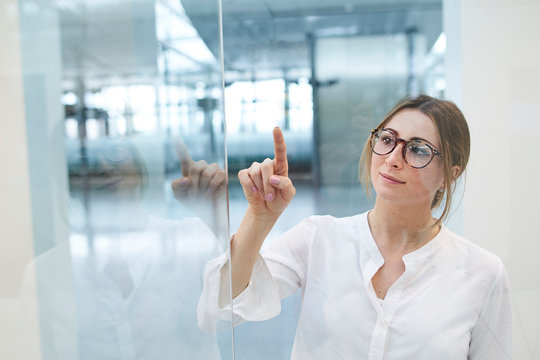 Young businesswoman touching virtual touchscreen
