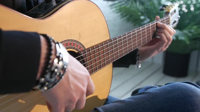 close-up of guitar strings and fingerboard, guitarist plays flamenco on acoustic guitar