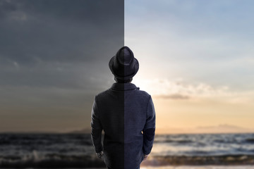 the guy in the hat view from the back, looking at the sea, concept happiness and depression, half...