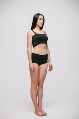 Obraz premium serious young model in black underwear standing on gray studio background. full length photo