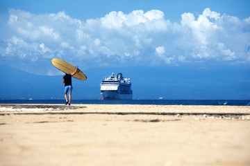 empty exotic travel background with ocean big ship, beach and surfer