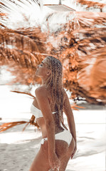 Wet sexy bikini female enjoying outdoor tropical shower at Maldives. Slim woman showering outside by palms at summer vacation. Blonde girl in white swimwear enjoying natural water on exotic beach.