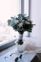White bouquet of flowers standing in a vase on the window