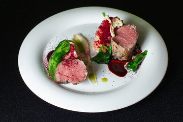 Beef steak with mashed potatoes decorated with greens on a white plate.
