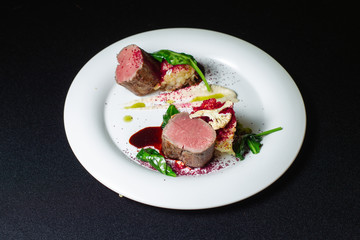 Beef steak with mashed potatoes decorated with greens on a white plate.