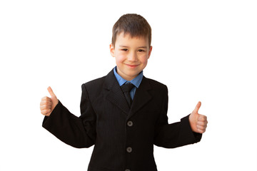 boy, schoolboy, in black business suit shows two hands a class, with a smile on his face