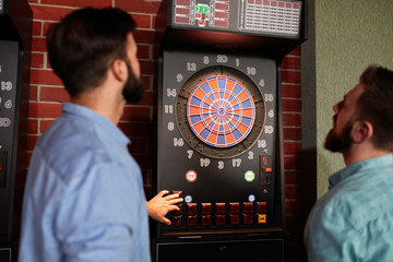 Two men playing darts setting electronic dartboard