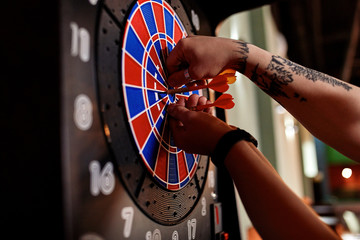 Close-up of tattooed man taking out darts from electronic dartboard