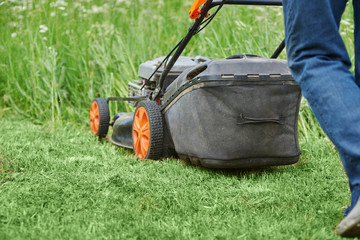 Man is using lawn mower on his countryside yard.