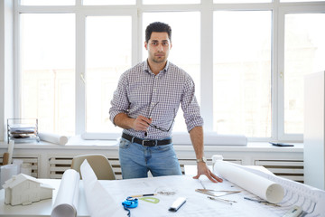 Portrait of handsome engineer posing at workplace an looking at camera, copy space