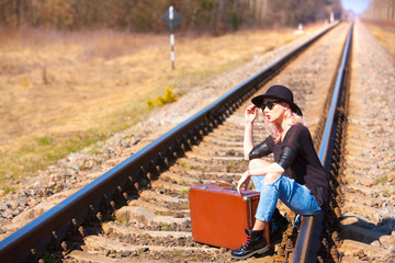 traveling beautiful woman with retro suitcase waiting for a train