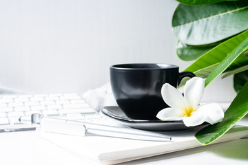 Coffee mug black with flower and leaves on  workspace