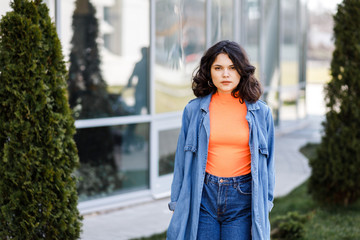 Young pretty girl walking on the street, dressed in jeans and denim shirt. Student weekdays