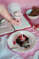 small babys hand reaches for the tasty homemade chocolate birthday cake decorated of some raspberries and candles served on the gentle pink background