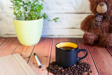 A Cup of coffee on a wooden table with a potted plant and toy bear