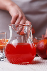 young woman in a gray apron squeezes juice of orange blood