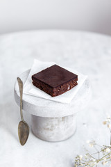Vegan raw brownies with nuts and dates, on white marble background with copy space. Healthy dessert concept