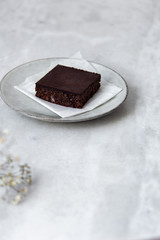 Vegan raw brownies with nuts and dates, on white marble background with copy space. Healthy dessert concept