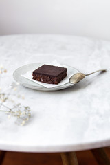 Vegan raw brownies with nuts and dates, on white marble background with copy space. Healthy dessert concept