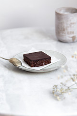 Vegan raw brownies with nuts and dates, on white marble background with copy space. Healthy dessert concept