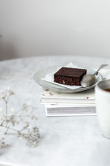 Vegan raw brownies with nuts and dates, on white marble background with copy space. Healthy dessert concept