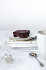 Vegan raw brownies with nuts and dates, on white marble background with copy space. Healthy dessert concept
