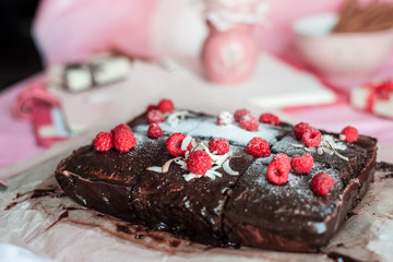 tasty homemade chocolate birthday cake decorated of some raspberries and candles served on the gentle pink background