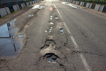 Fototapeta premium there are many potholes on the roadway close up