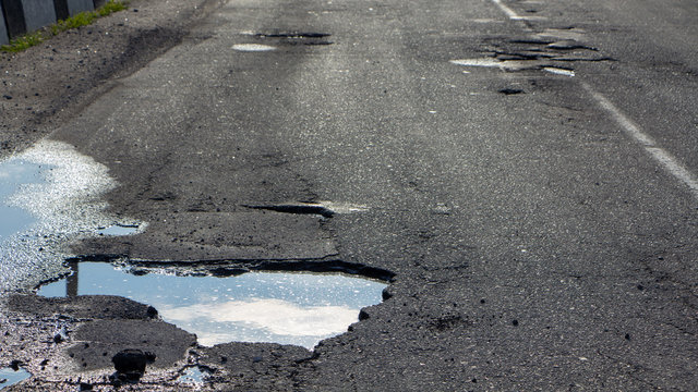 there are many potholes on the roadway close up