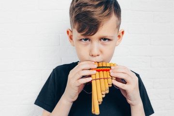 Boy playing on bamboo pan flute. © meteoritka