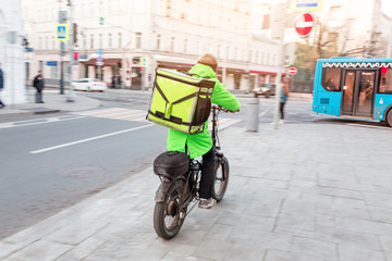 Fototapeta na wymiar Delivery man with backpack full of tasty food riding bicycle on sidewalk, motion blur effect