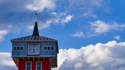 Clock tower near the fire station against the blue sky with fast moving clouds - time lapse. 4K. Close up.