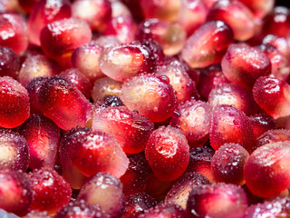 Macro shot of fresh pomegranate seeds with water droplets.