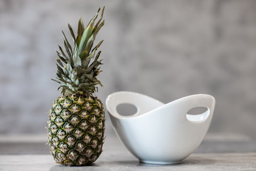 Ananas przy białej misce na betonowym tle © andsko