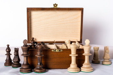 carved wood chess pieces in wooden box on white background