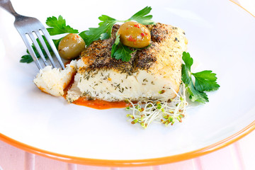 Halibut filet on a plate garnished with sprouts, olives, parsley, and tomato sauce