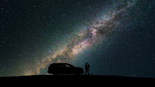 The Man And Woman Standing Near Tree Against The Meteor Shower. Time Lapse