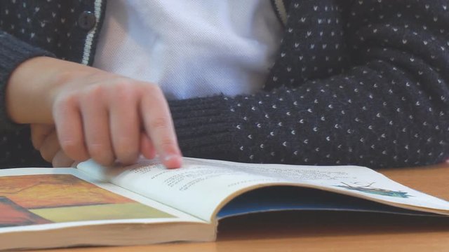 Schoolboy reading, moving fingers on the book