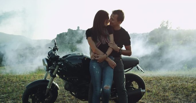Black old motorcycle and a young coupe traveling through the nature exploring the landscape , enjoying the time together.