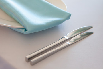 White plate with a turquoise napkin, metal fork and knife, table setting wedding