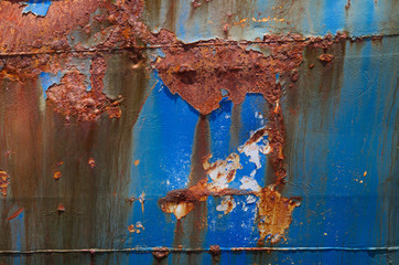 Detail of a heavily corroded ship: blue paint peeling off 