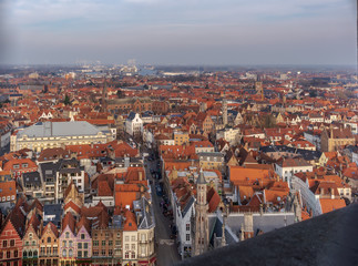 Fototapeta na wymiar Fantastic Bruges city skyline with red tiled roofs and numerous churches' towers in sunny winter day. View to Bruges medieval cityscape from the top of the Belfry Tower.
