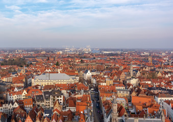 Fototapeta na wymiar Fantastic Bruges city skyline with red tiled roofs and numerous churches' towers in sunny winter day. View to Bruges medieval cityscape from the top of the Belfry Tower.