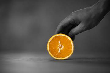 Pomarańcza na stole trzymana przez dłon - obrazy, fototapety, plakaty