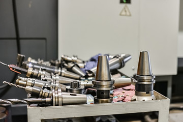 Mandrels and accessories for the CNC milling machine are located on the machine near the industrial equipment. Drills, cutters, cutters for metal processing.